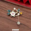 Macro view of elegant vintage floral brooch with enamel leaves and hanging pearl detail - 370# Kingfisher Style Flower Lock