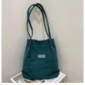 Detailansicht der dunkelgrünen Cord-Eimertasche mit Fashion-Label und weicher Textur - Grün