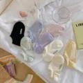 Detailweergave van kleurrijke pastel enkelsokken met 'hello.' borduurwerk op wit beddengoed. - Eén Maat (35-40) / Groen
