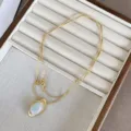 Primo piano di una collana dorata con pendente in agata ovale su vassoio portagioielli - Collana con Pendente in Agata Ovale