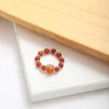 Detailed macro shot of a luxury red agate beaded ring with central gold gemstone - One Size / Red