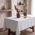 Minimalist off-white washed cotton tablecloth displayed on a rustic wooden dining table - Custom Size / Off White