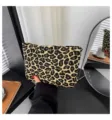 Detailansicht einer modischen Kosmetiktasche mit Leopardenmuster, in der Hand gehalten. - Leopardenprint