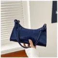 Close-up view of dark blue patent leather shoulder bag with a luxury crocodile texture - Blue