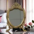 Detailed close-up of the vintage gold carved vanity mirror with delicate floral and bow motifs. - 21*33cm / Gold