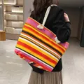 Grote gestreepte canvas draagtas in etnische stijl voor dames vanaf de achterkant van model - Regenboog Streepjesprint (Stijl 7)