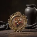 Close-up detail of vintage round gold photo frame with floral art for elegant tabletop decor. - Inner: 9.5*9.5 Outer: 16*16 CM / Regular
