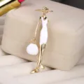 Close-up detail of an elegant lady brooch with white enamel and gold-plated finish. - Fashion Lady (5067410072136) / Gold And White