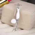 Detailed close-up of fashion lady brooch with white enamel on a jewelry display box. - Fashion Lady (5067410072138) / Silver And White