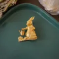 Primer plano detallado de un broche de conejo jardinero dorado vintage con regadera y rastrillo - Estilo Conejo Dorado Con Tetera