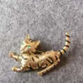 Dettaglio di una spilla a forma di gatto vintage dorata con occhi verdi e strisce nere. - Forma di Gatto Vintage (B2) / Oro