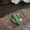 Macro view of green enamel cactus brooch showing rhinestones and white pearl texture - Cactus Shape