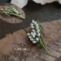 Close-up detail of a vintage lily of the valley brooch featuring enamel leaves and pearls - Long Lily of the Valley