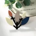 Eleganter Zweig-Brosche mit bunten Blattelementen auf einem schwarzen Metallrahmen für Damen - Off-White Grau Blau Mix