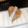 Vista macro dettagliata di una lussuosa spilla ad ali di angelo dorata con strass di cristallo - Oro