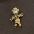 Close-up of a vintage golden scarecrow brooch featuring pearls and green rhinestones. - Vintage Scarecrow Style