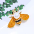 Detail van gouden bijenbroche met oranje geëmailleerde vleugels en witte parel - Bijstijl (Stijl 6)
