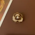 Macro detail of a vintage camellia brooch with white enamel petals and a central pearl - French White Camellia Style