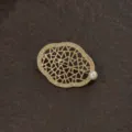 Detailaufnahme einer goldenen Vintage-Brosche im Barockstil mit Perlenakzenten. - Barockes hohles geometrisches Design