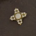 Nahaufnahme einer goldenen Vintage-Barock-Kreuzbrosche mit eleganten weißen Perlen - Barockes Vintage-Kreuz-Design