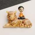 Close-up macro view of a vintage alloy tiger brooch with a small meditating figure - Zen Figurine on Tiger Gold