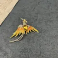 Detailed view of a vintage gold-plated phoenix brooch with yellow enamel and crystals - Golden Phoenix Style