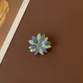 Detailed close-up of a vintage baroque enamel flower brooch with blue and green petals - Retro Blue and Green Sun Flower