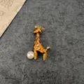 Detailed view of a vintage giraffe brooch with orange enamel and a small pearl. - Giraffe Style