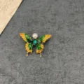 Detailed macro view of a vintage Baroque butterfly brooch with green yellow enamel and pearl - Butterfly Design