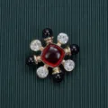 Close-up detail of a vintage Baroque style brooch with a red central stone and black beads - Style 11