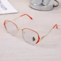 Detail of retro gold-red metal frame glasses with anti-blue light lenses on a desk. - Gold & Red Frame / Photochromic Anti-Blue Light