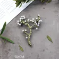 Macrodetail van de vintage plantentakbroche met elegante witte parels op een grijze ondergrond. - Brons Groene Parel Tak Stijl (SMT1005003927850261)