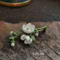 Detail view of handmade enamel lily of the valley brooch on rustic wood background - 3-Pearl Lily of the Valley