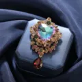 Elegant vintage floral brooch featuring a heart-shaped iridescent crystal and red drop - Gold Heart Iridescent Crystal