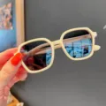 Detaillierte Nahaufnahme einer cremefarbenen Kindersonnenbrille mit UV-Schutz - Gebrochenes Weiß