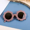 Dusty rose flower-shaped sunglasses for kids with dark lenses on a modern background - Coffee Frame Tea Lens