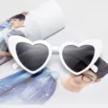 Trendy white heart-shaped party sunglasses with dark lenses on a fashion magazine - White Frame / Black Lens