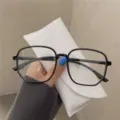 Close-up view of stylish oversized black polygonal glasses frame for women with white pouch - Black Frame Blue Film Plain Lens / Black