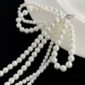 Macro view of elegant multi-strand white pearl shoe charms with silver ring connection - Bowknot Pendant Style / White