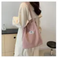 Vista detallada de un bolso shopper de pana rosa llevado por una modelo de moda con estilo. - Rosa