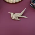 Detailed macro view of a vintage matte gold bird brooch with Egyptian relief textures - Egyptian Relief Bird Style / Matte Gold