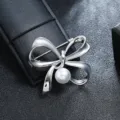 Detail view of a vintage silver metal bow brooch with a central white pearl. - Silver Bow Pearl Style