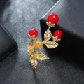 Close-up of a vintage gold-tone floral brooch pin featuring red berries and matte leaves - Gold Red Bead Plant Corsage Style / Gold