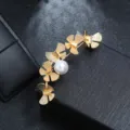 Close-up of a vintage matte gold floral brooch with a white pearl accent - Curved Butterfly Leaf Pearl Style