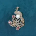 Detailed view of a vintage gold-toned peacock brooch with pink crystals and a large pearl. - Red Phoenix