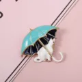 Close-up of a cute white cat under a blue enamel umbrella brooch with gold trim - Blue Umbrella White Cat Brooch