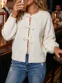 Close-up of women's white knit cardigan featuring chic front bow ties and round neckline style. - S / White