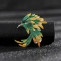 Detailed macro view of an elegant vintage wing brooch with green enamel and white crystals - Style 3 (Gradient Green Gold Wing)