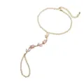 Détail élégant d'un bracelet-bague doré orné de cristaux de tulipes roses raffinés. - Tulip Ring-Linked Bracelet / Rose