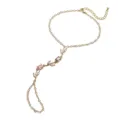Gros plan détaillé sur la parure de main dorée avec motif tulipe en zircon rose. - Tulip Ring-Linked Bracelet / 紫色和粉色